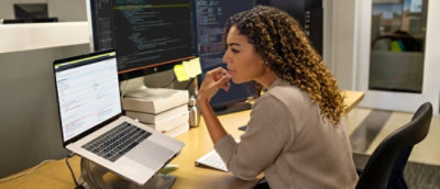 A woman sitting at a desk looking at a computer screen.