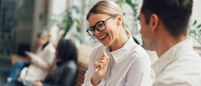 Женщина в очках улыбается.