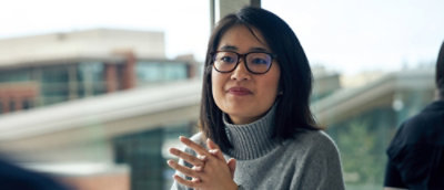 Женщина в очках с руками, сложенными вместе.