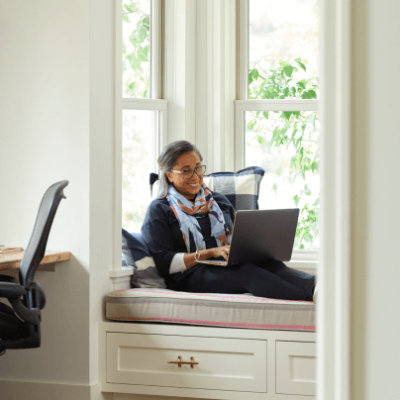 A women sitting on sofa and laughing while talking over a laptop