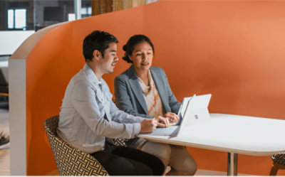 Zwei Personen, die an einem Tisch in einem Büro zusammenarbeiten.