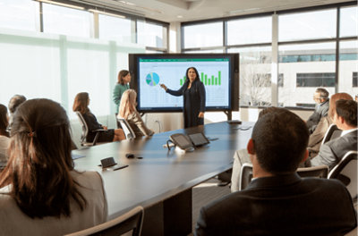 Een vrouw die een presentatie geeft tijdens een vergadering met behulp van de projector terwijl andere mensen zitten