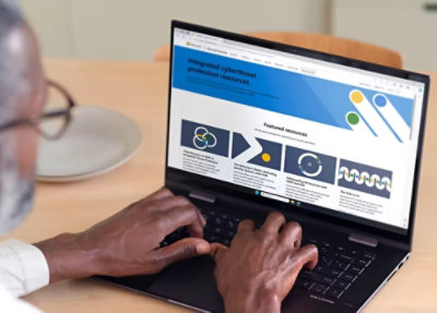 在螢幕上顯示網路威脅防護資源的膝上型電腦上打字的人。