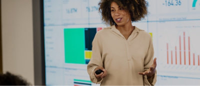 Una mujer está haciendo una presentación delante de una pantalla grande.