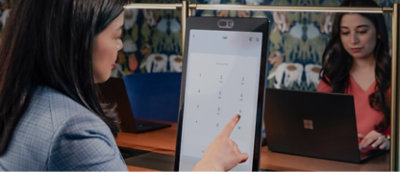 Una mujer apunta a una pantalla delante de un portátil.