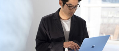 Muž v černé bundě používající laptop.