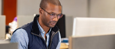 Un homme portant des lunettes et regardant un écran d'ordinateur.