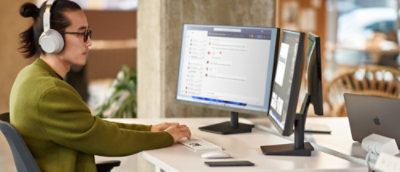 صورة لشخص يرتدي سماعات رأس ويجلس إلى مكتب به شاشتان للكمبيوتر.