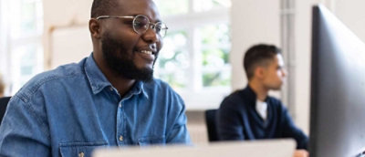 A man with glasses staring at a screen