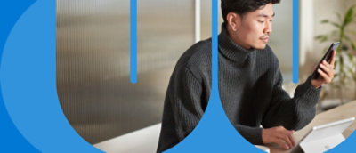 Човек в черен пуловер, който гледа мобилния си телефон