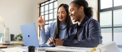 Two people smiling while looking at a laptop.