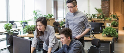 Three people are engaged looking at a laptop.