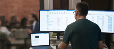 A man in a green shirt looking at a computer screen.