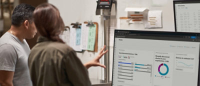 A woman explaining a man using a whiteboard and a screen.