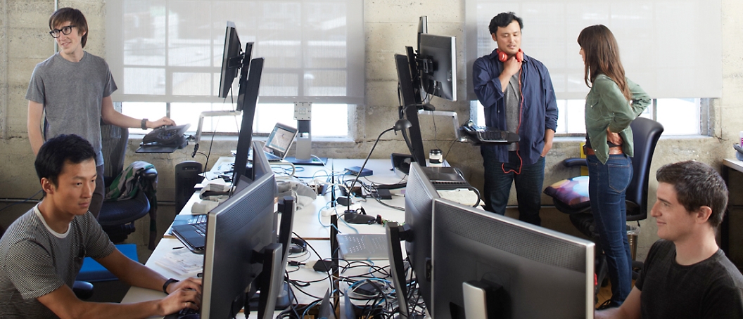 En gruppe personer på et kontor arbejder på en stationær computer og diskuterer