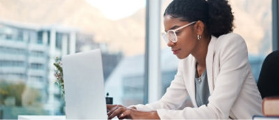 一位穿白色西装戴着眼镜的女士正在电脑前工作。