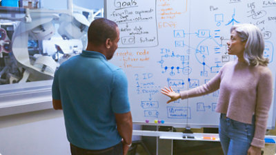 A two person standing in front of a whiteboard