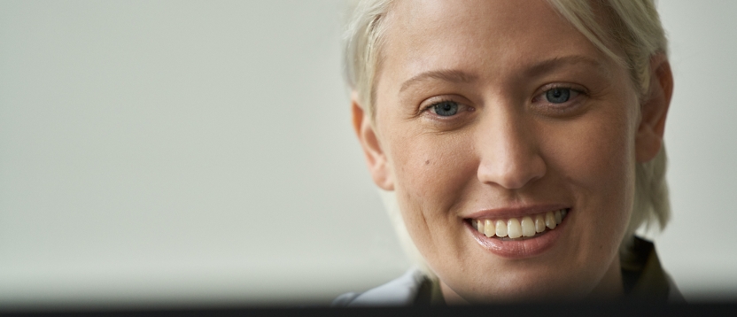 Eine Frau, die vor einem Computerbildschirm lächelt.