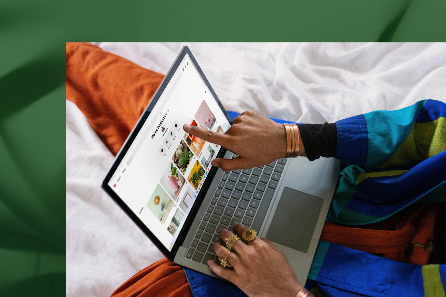 A person touches the screen of their Sage Surface Laptop 5 while working in bed.