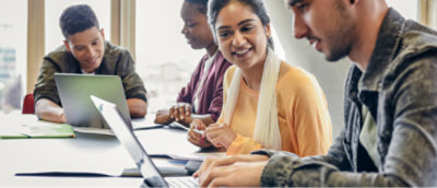 Group of individuals engaged in a meeting with laptops on a table.