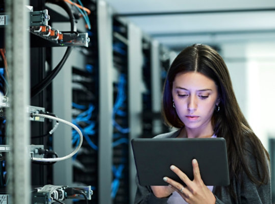 A person in a server room holding a tablet device