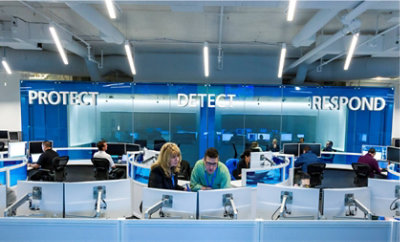 Orang yang bekerja di kantor dengan kata Lindungi, Pertahankan, dan Respons terpampang dinding.