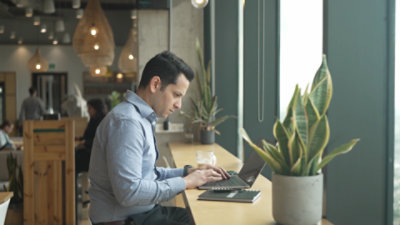 A person sitting at a high top table typing on a laptop