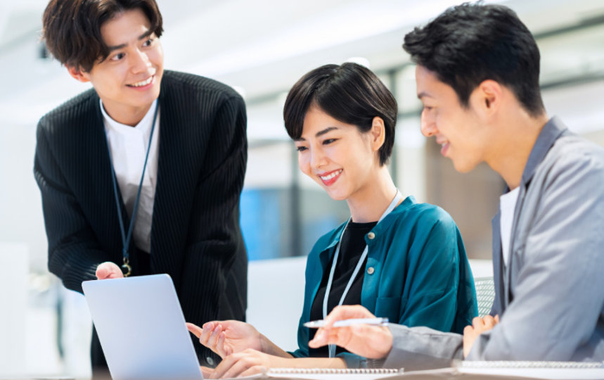 ノート PC を見ながら笑顔で話しをする 3 人のビジネス パーソン