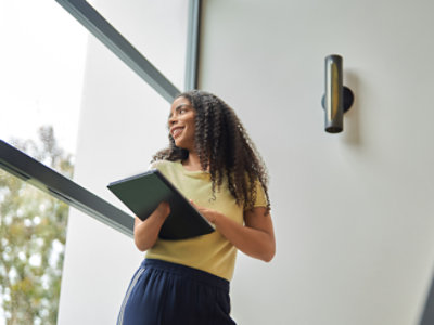Una mujer sostiene una tableta frente a una ventana
