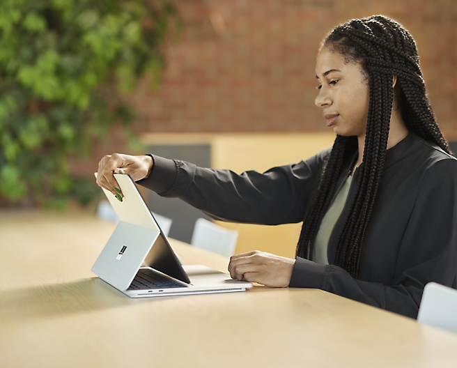 一位女士坐在椅子上，手里拿着她的 Microsoft Surface Pro