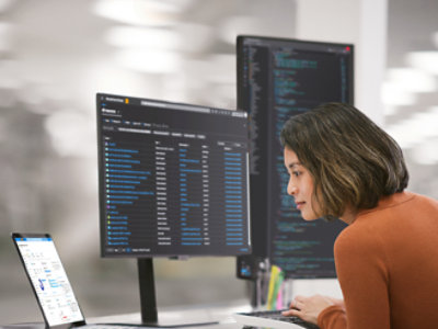 Una mujer sentada en un escritorio con dos monitores