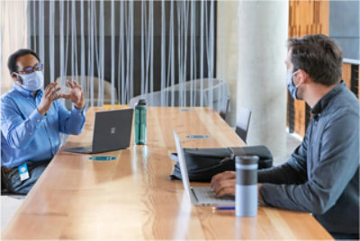 Two people wearing masks having a meeting in a conference room