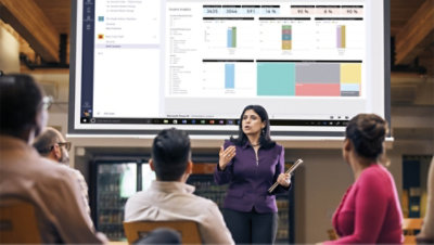 仕事仲間の部屋に対してプレゼンテーションを行うプロジェクター画面の前に立っている人