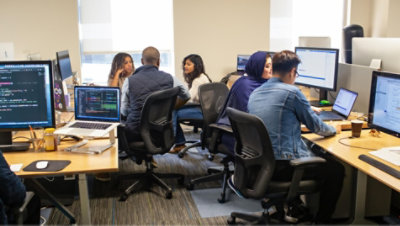 People having conversations and working together in at desks in an office