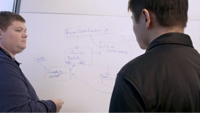 Two people having a conversation and drawing a diagram on a whiteboard