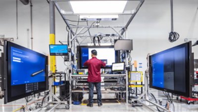 Ein stehender Arbeiter, der an seinem Schreibtisch mit vielen Bildschirmen arbeitet