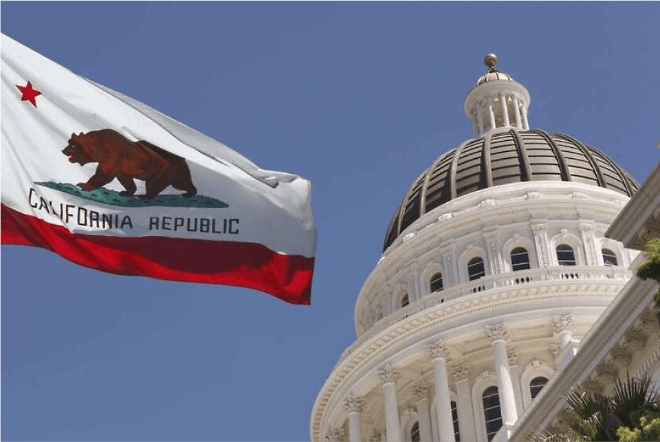 Vlajka státu Kalifornie vlající před vládní budovou
