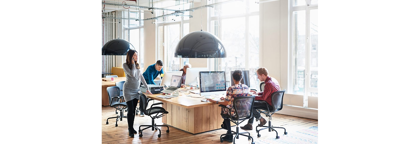 Vijf mensen die aan hun bureaus in een kantoor werken