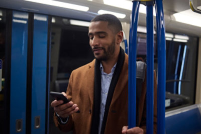 Человек стоит в поезде и использует мобильный телефон