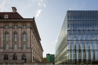A newer glass building next to an older stone building