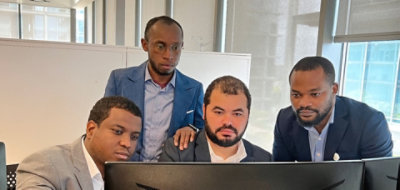 Vier Personen, die einen Desktopmonitor betrachten