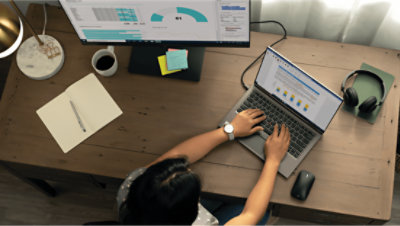 一個人坐在桌前使用膝上型電腦和桌上型電腦螢幕工作的鳥瞰圖