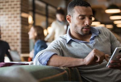 A person in a casual office environment looking at a smartphone