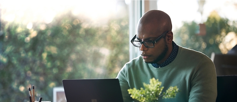 En mann som arbeider på en bærbar datamaskin foran et vindu.