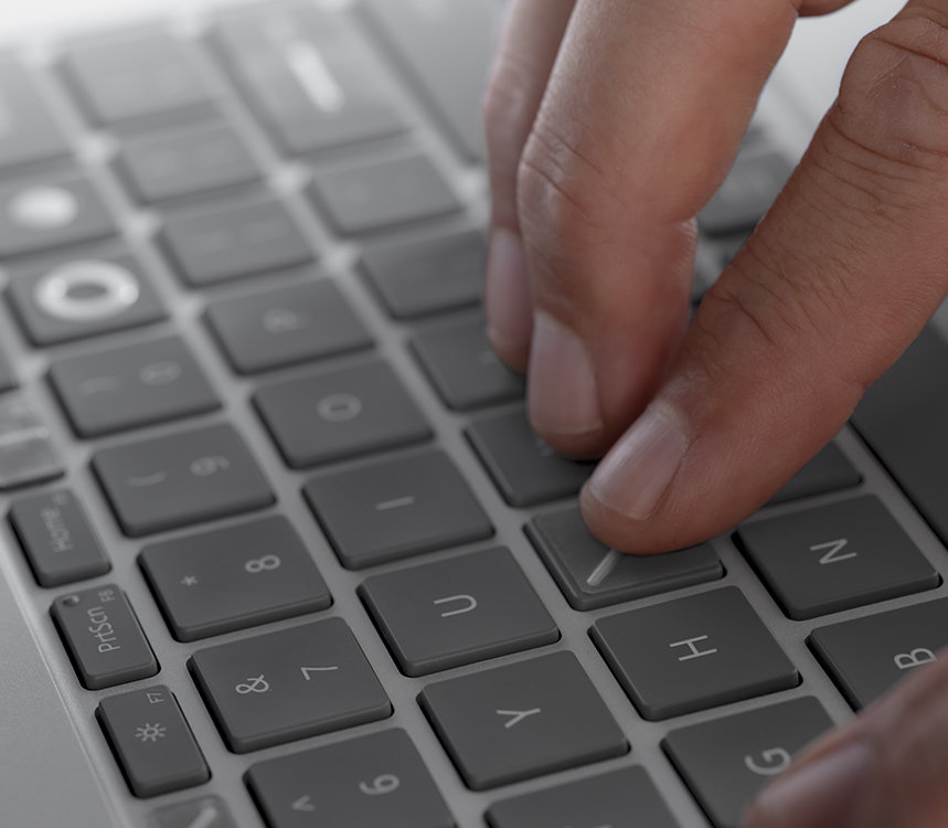 A mão de uma pessoa a utilizar os marcadores de teclado do Kit de Acessibilidade da Microsoft para localizar a tecla correta no seu dispositivo.