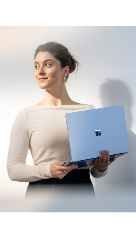 A person holding a 13.8" Surface Laptop in Sapphire.