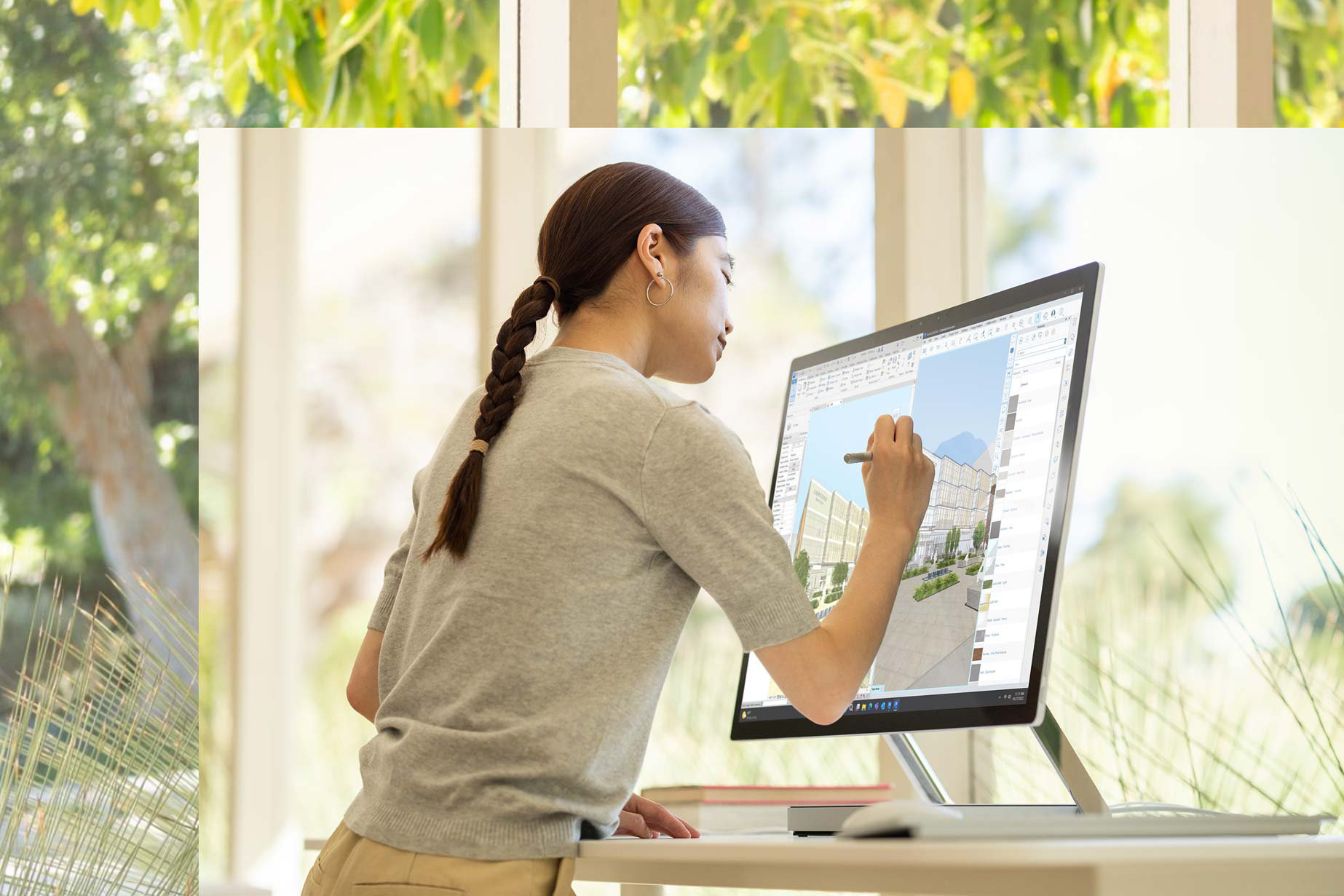 Iemand staat voor een Surface Studio 2+ en tekent op het scherm met de Surface Pen om een ontwerp te maken.
