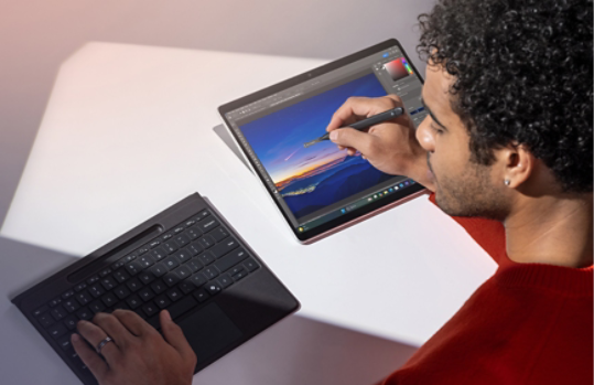 Eine Person verwendet Surface Pro Flex Keyboard in nicht angebrachtem Zustand und Slim Pen, um ein Foto auf ihrem Surface Pro zu bearbeiten.