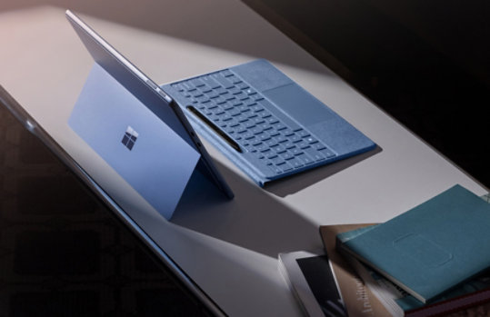 Surface Pro in Saphirblau auf einem Tisch mit Surface Pro Flex Keyboard (nicht angebracht) und Slim Pen.