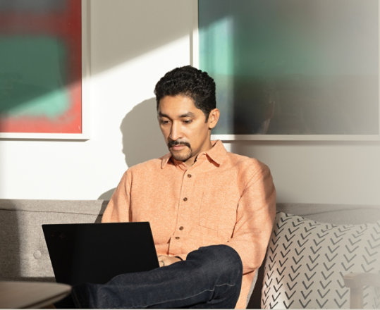 En person använder Microsoft 365 på en bärbar dator i ett sällskapsrum.